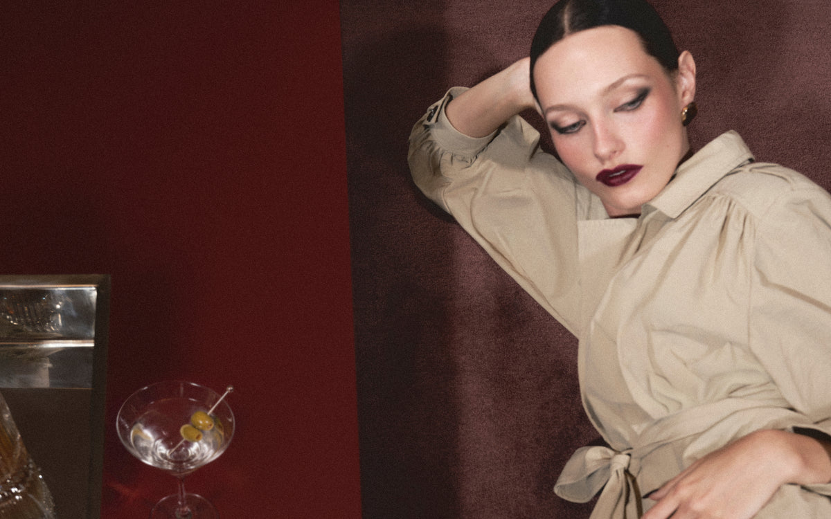 A woman wearing a deep red lipstick and blush lies on the floor next to a coffee table